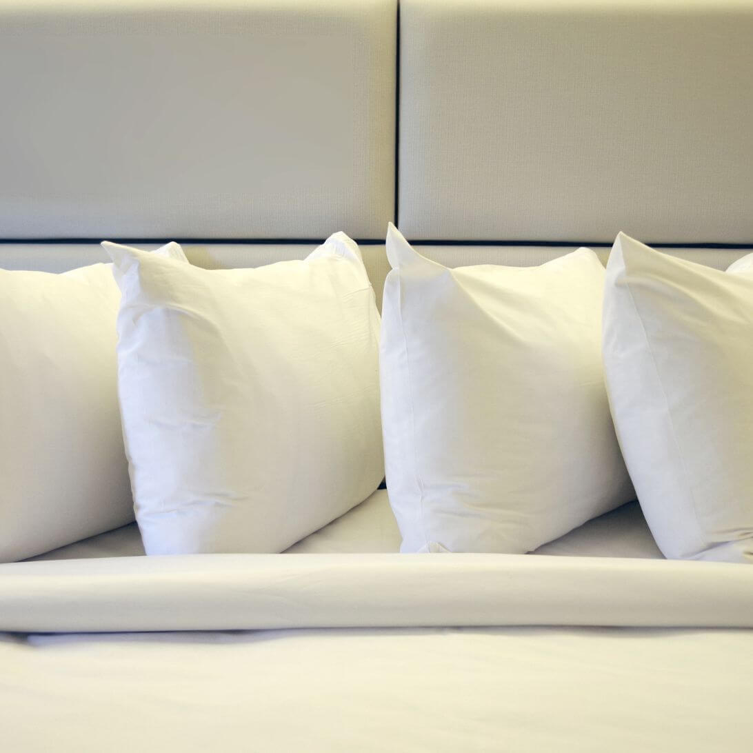 Verschillende hoofdkussens op een rij op bed