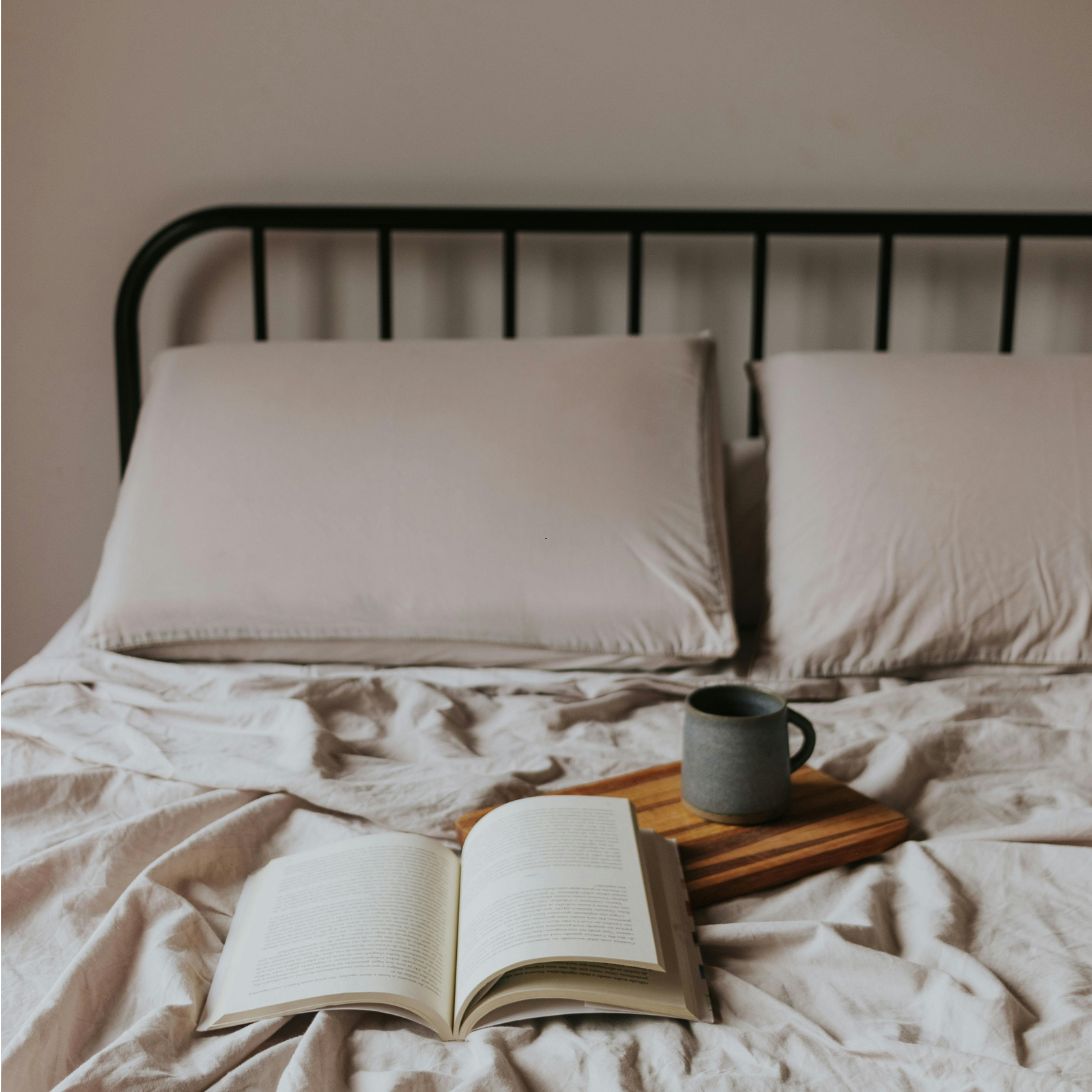 Opgemaakt bed met boek, kopje en Wopilo Plus kussens