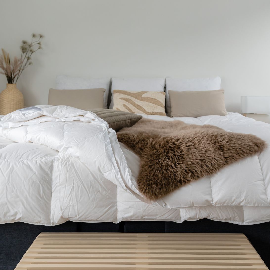 Opgedekt bed met dekbed zonder overtrek, kussens en plaid