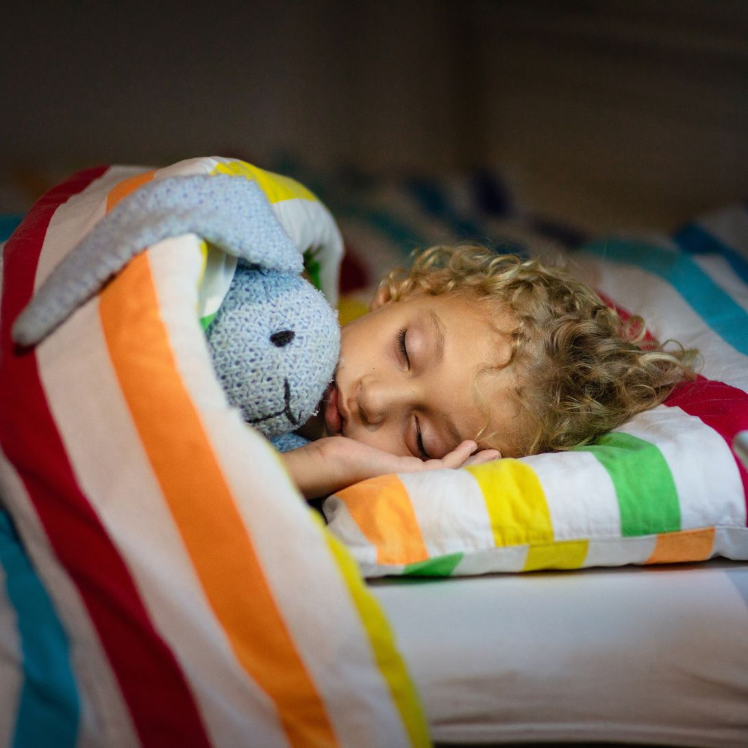 Kind ligt met knuffel te slapen in kinderbed